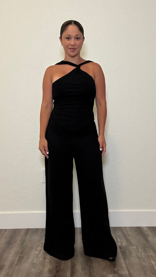Woman wearing a black jumpsuit with knot detail around neck