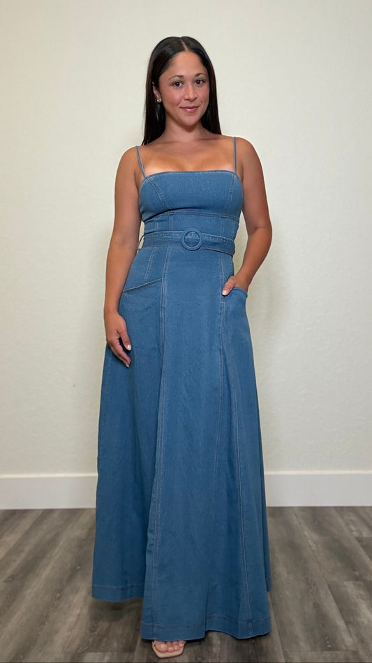 Woman wearing a denim maxi dress with spaghetti straps and waist tie buckle