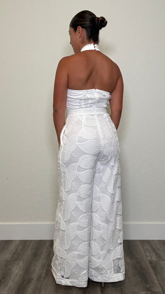 Woman wearing a white lace jumpsuit with open back and halter tie