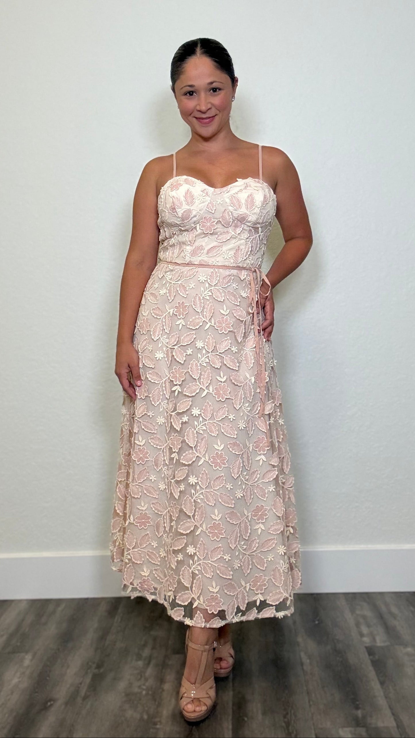 A woman modeling a light pink floral embroidery strapless maxi dress with a sweetheart neckline and a fitted, flared skirt