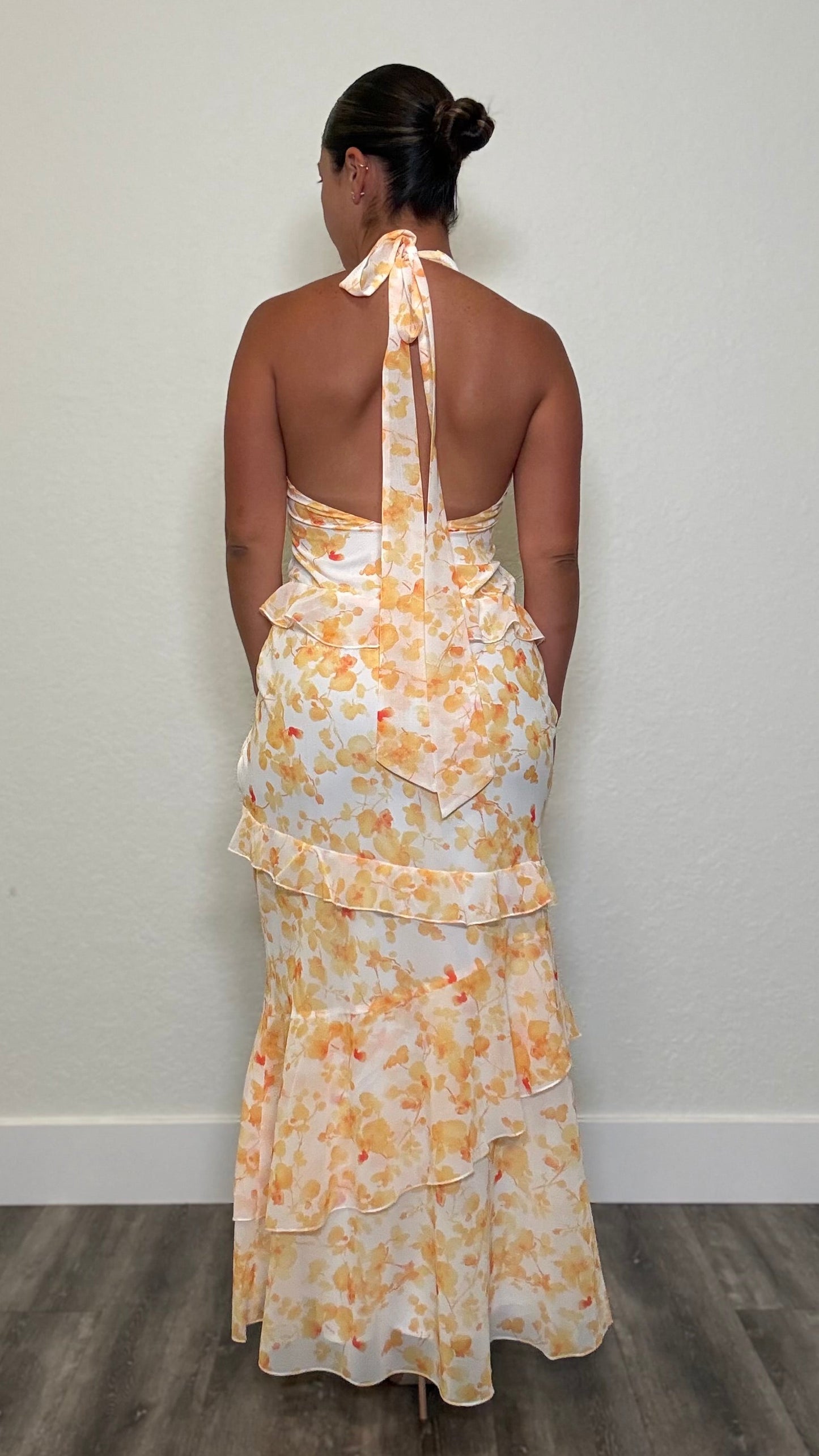 Woman wearing a white with yellow florals with an open back  and halter tie
